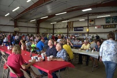 A large group of people are sitting at long tables in a large room.