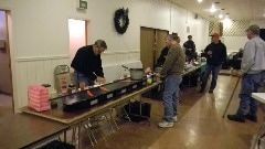 A group of men are standing around tables in a room preparing food.