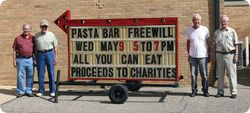 A group of men standing in front of a sign that says pasta bar freewill