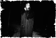 A black and white photo of a woman standing in the dark