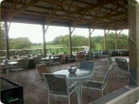 A patio area with tables and chairs under a canopy.