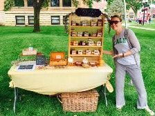 A woman is standing in front of a table with jars on it.