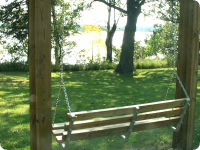 A wooden swing is hanging from a wooden post in a park