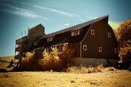 A large brown barn is sitting in the middle of a field.