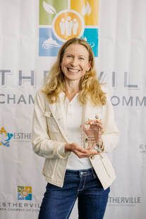 A woman is holding a trophy in front of a wall.