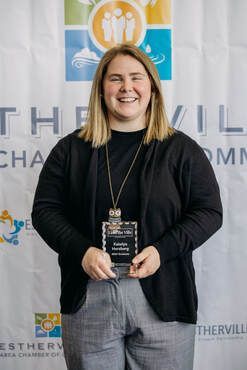 A woman is holding an award in front of a wall.