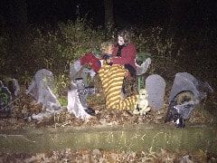 Two children are sitting on a bench in a cemetery at night.