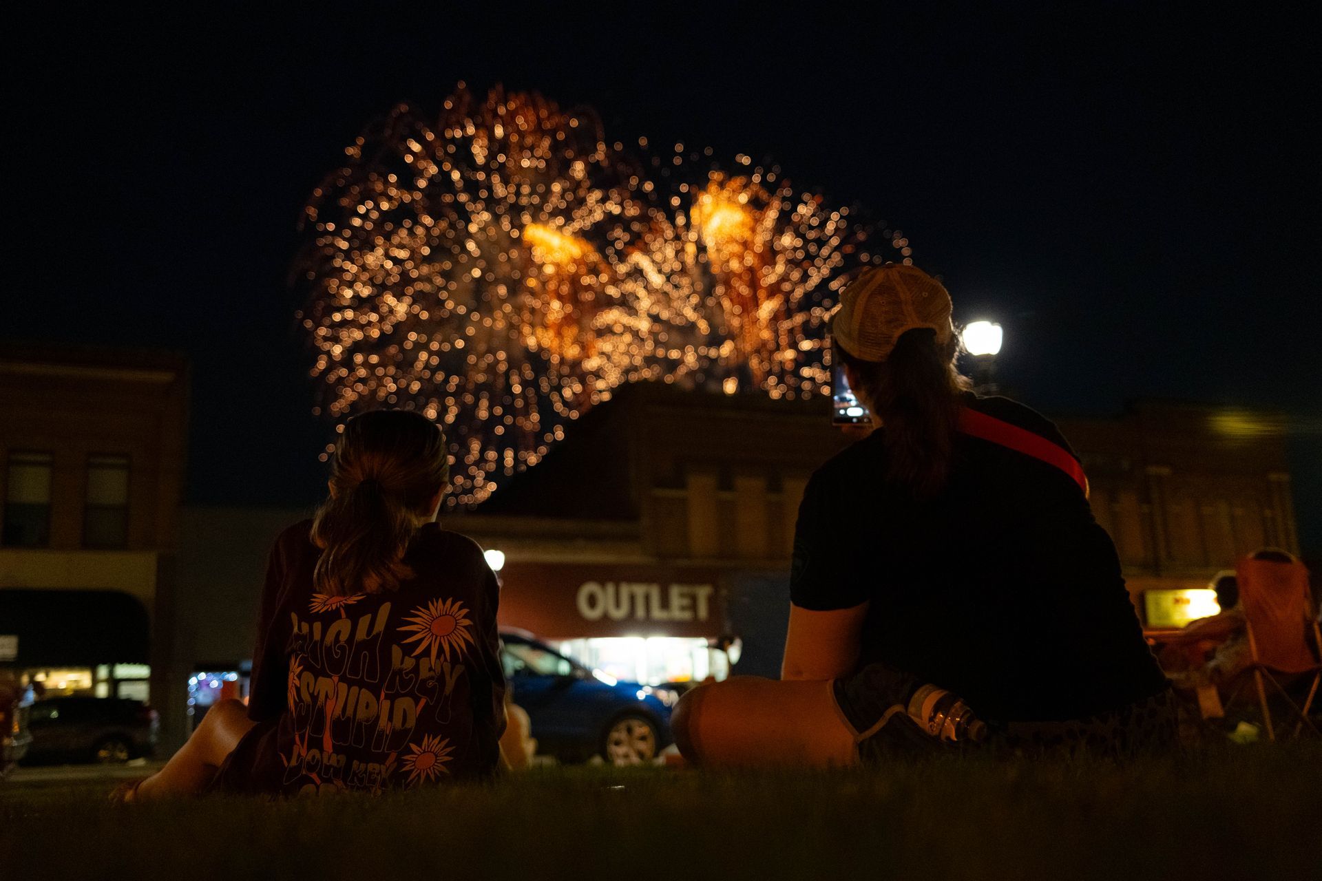 A group of people are watching fireworks in a park.