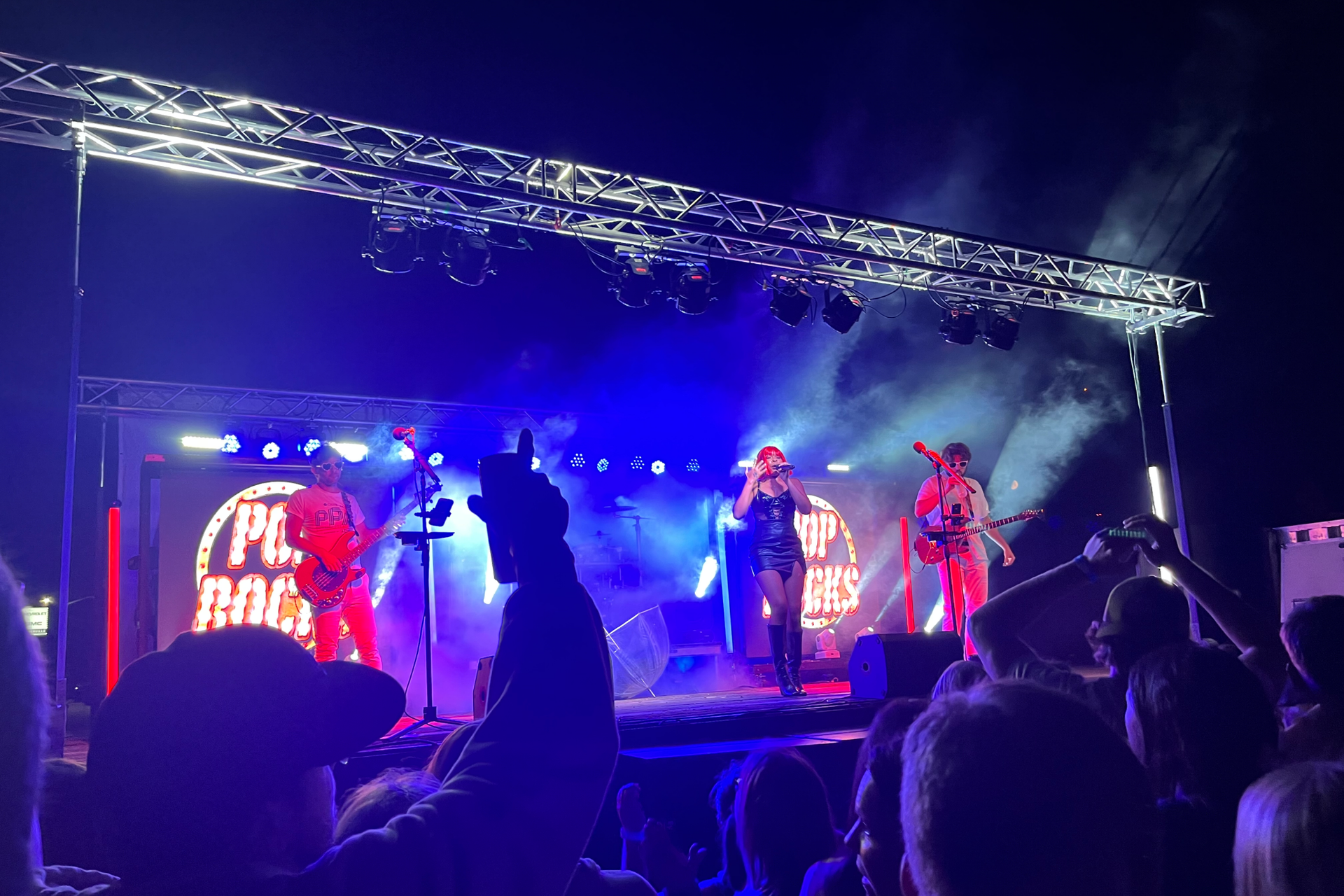A crowd of people are watching a band on stage at a concert.