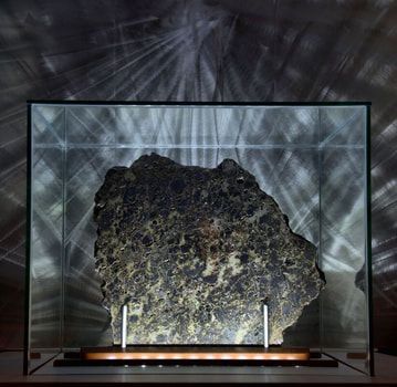 A large rock is displayed in a glass case.