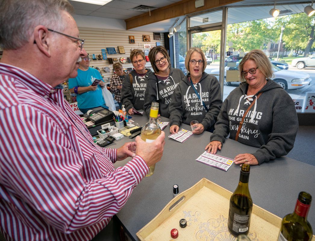 A group of people are sitting around a table with bottles of wine.