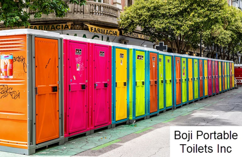 A row of colorful portable toilets are lined up on the side of the road.