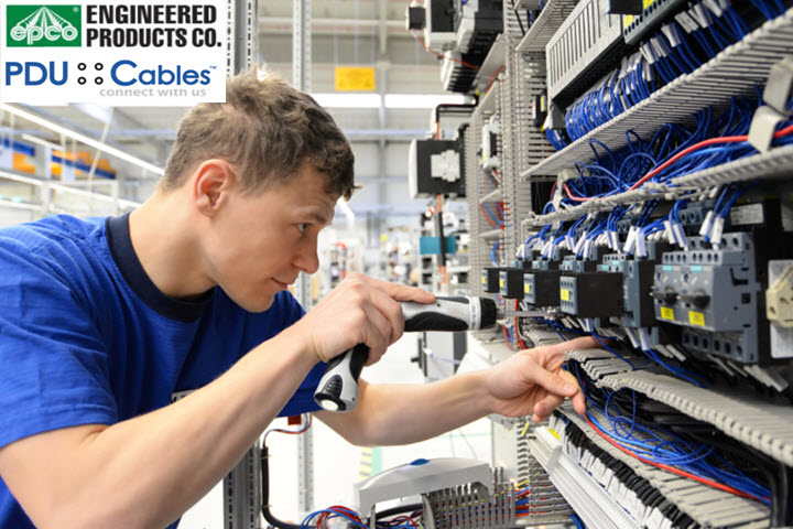 A man in a blue shirt is working on an electrical panel.