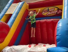 A young boy is jumping on top of an inflatable slide.