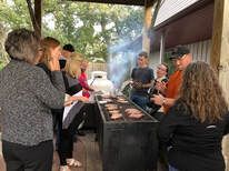 A group of people are standing around a grill cooking food.