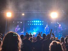 A crowd of people are watching a band on stage at a concert.