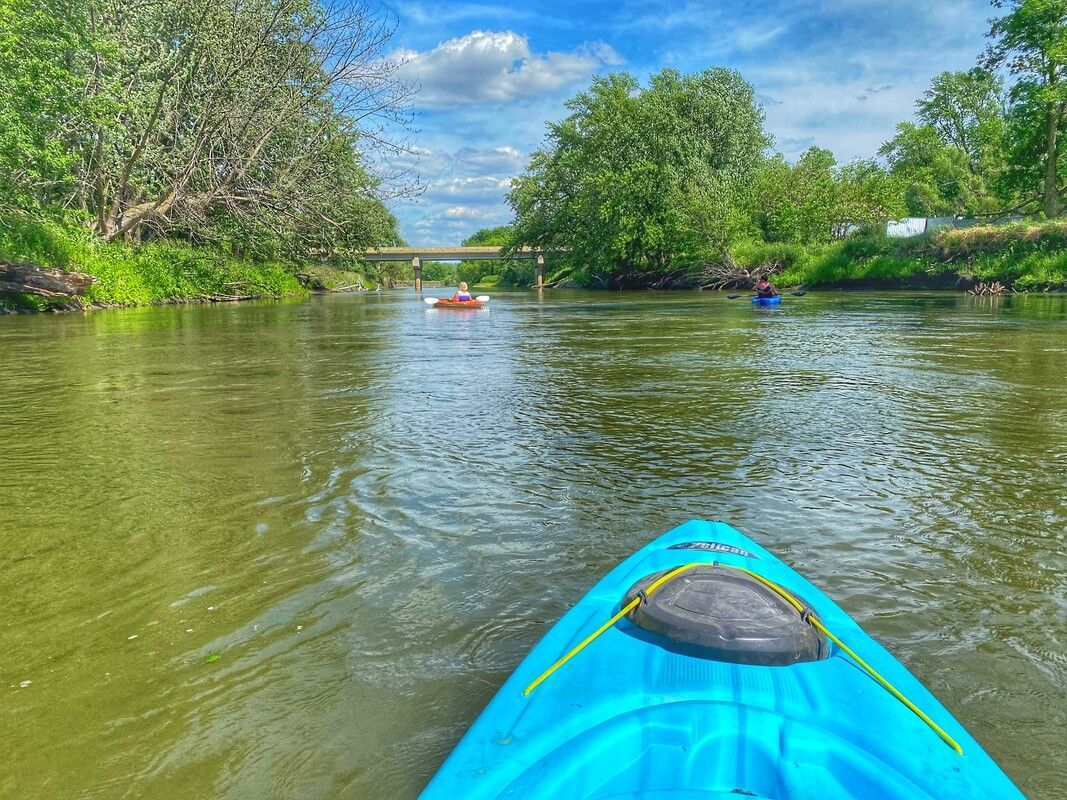 A person is paddling a blue kayak down a river.