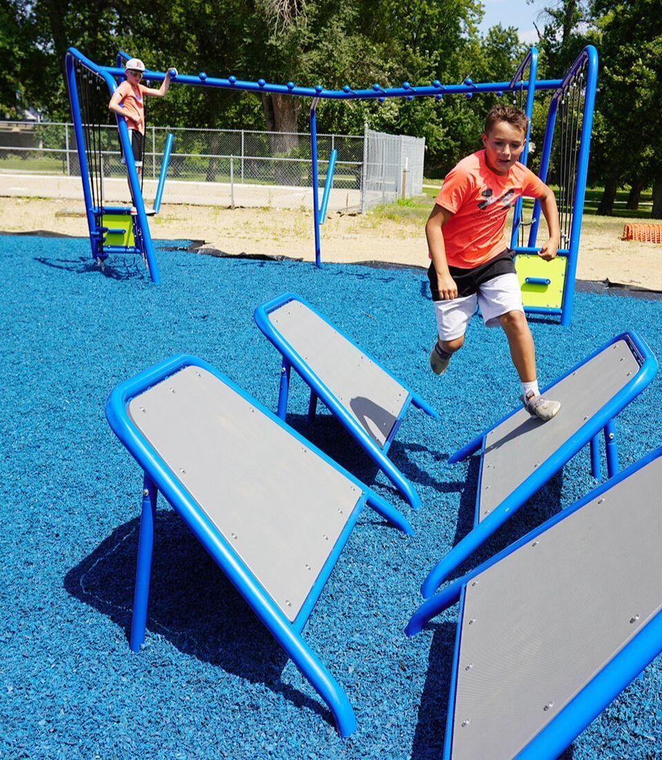 A boy in an orange shirt is running on a playground