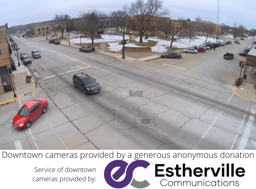 A red car is driving down a street next to a sign that says esterville communications