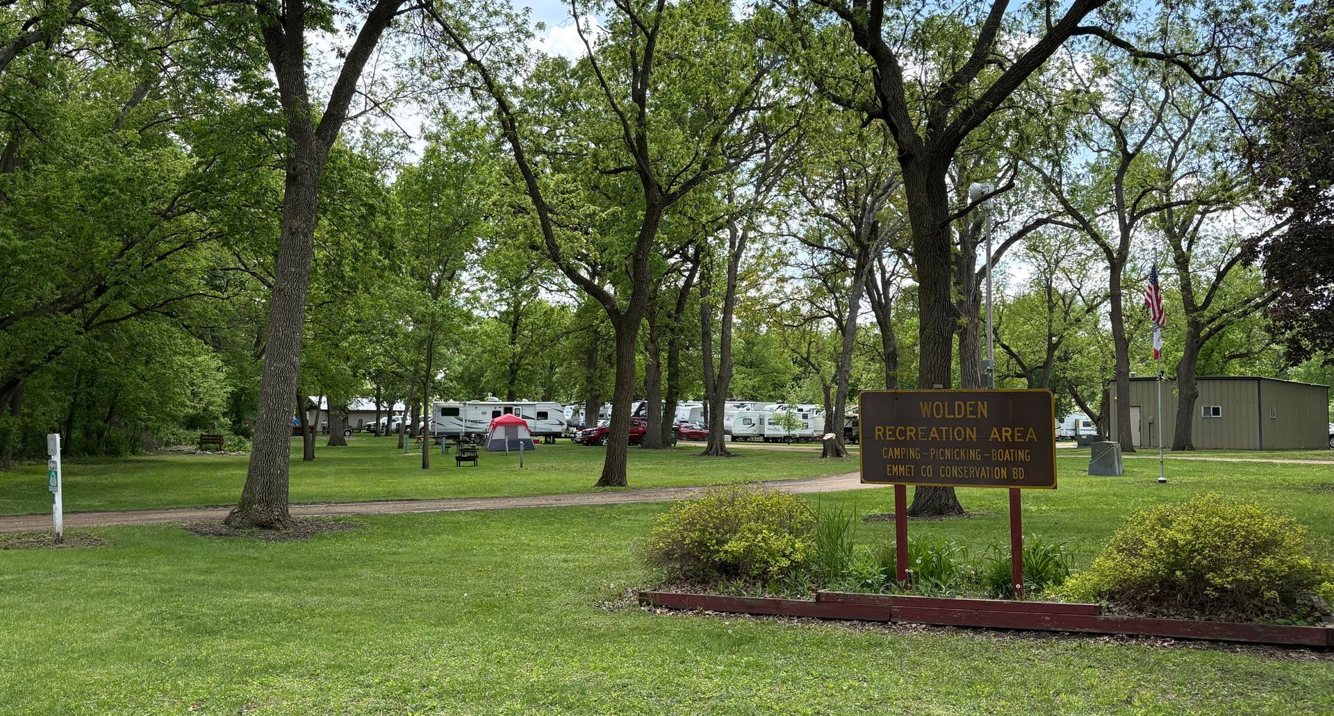 A wooden swing is hanging from a wooden post in a park