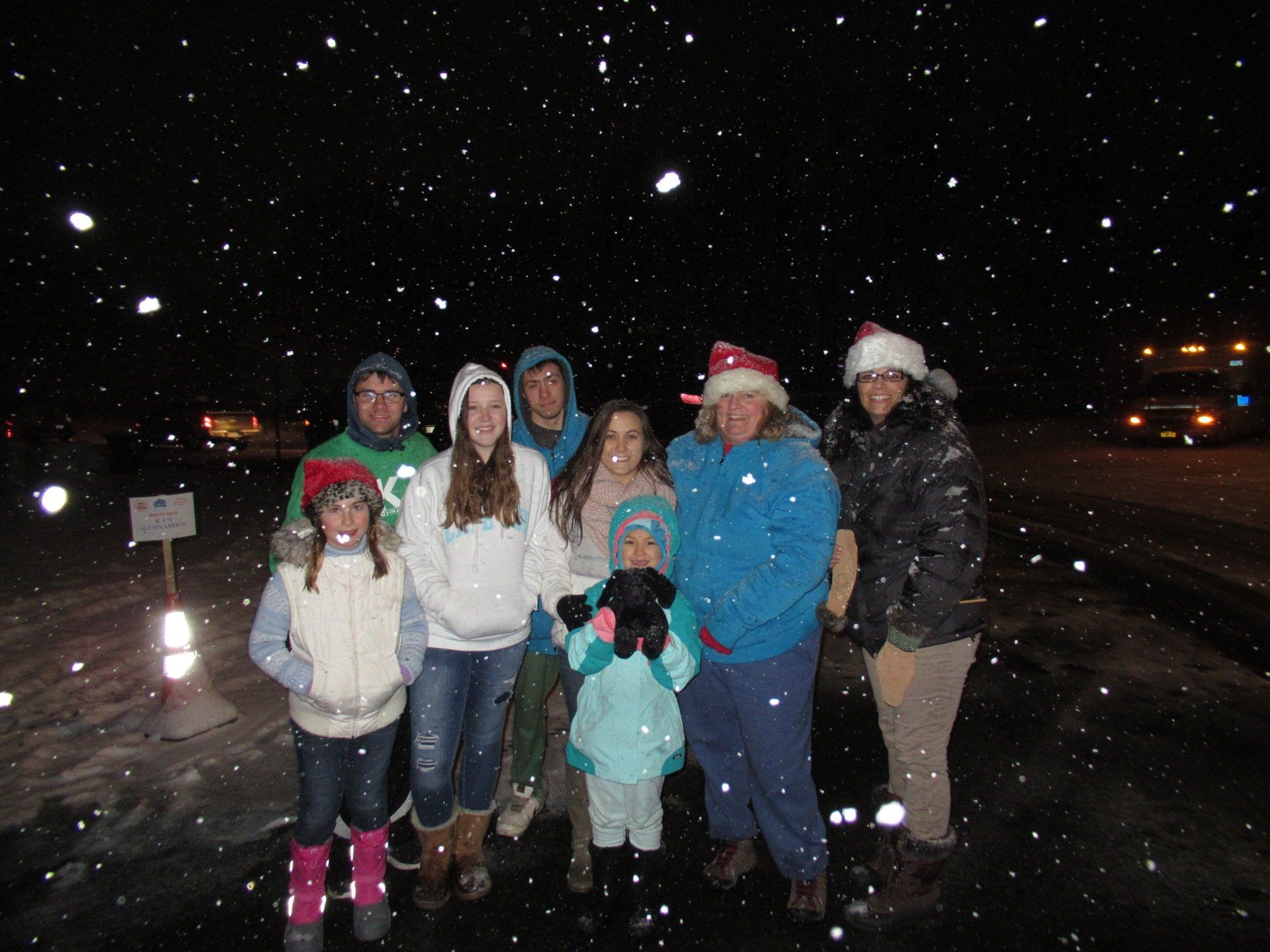 A group of people standing in the snow wearing santa hats