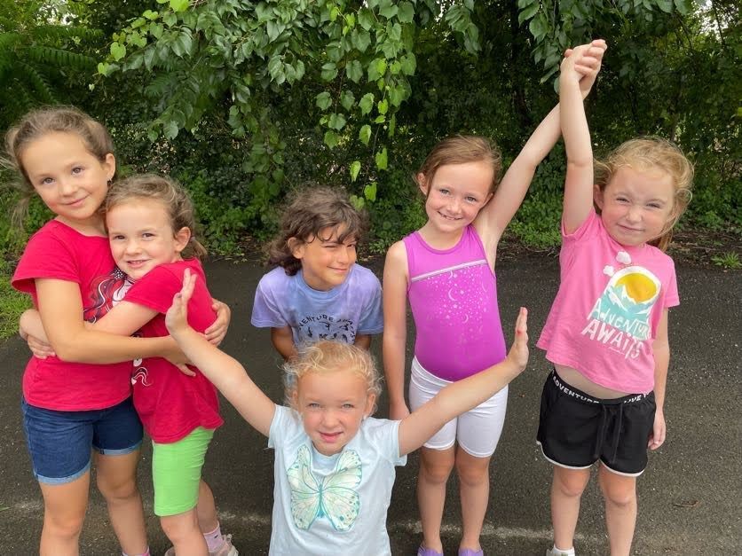 A group of young girls are posing for a picture with their arms in the air.