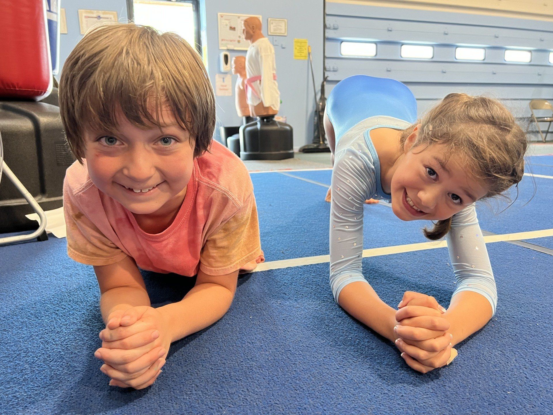 A boy and a girl are doing plank exercises on the floor.