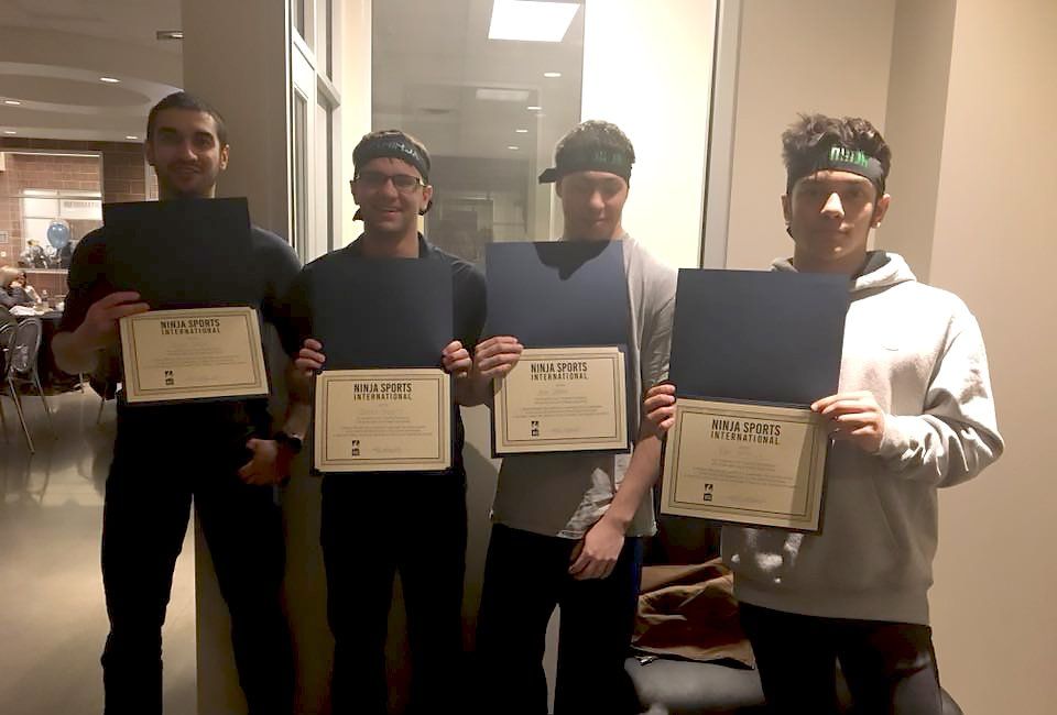 A group of young men are standing next to each other holding certificates.