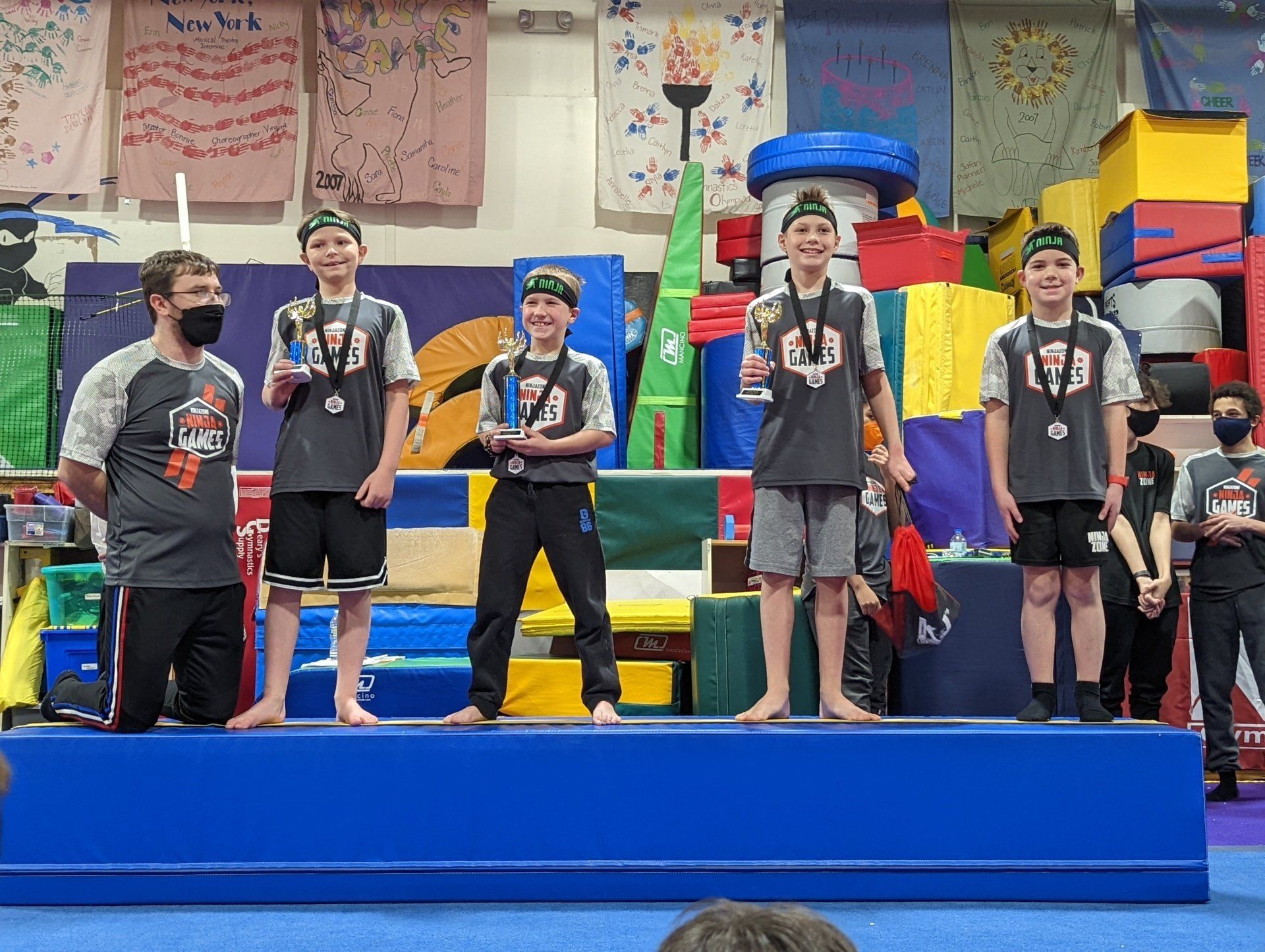 A group of young boys are standing on a podium holding medals.