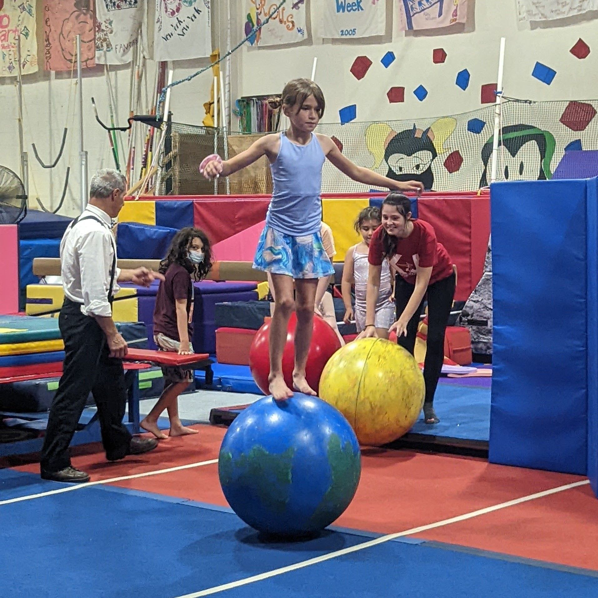 A girl is balancing on a ball in a gym