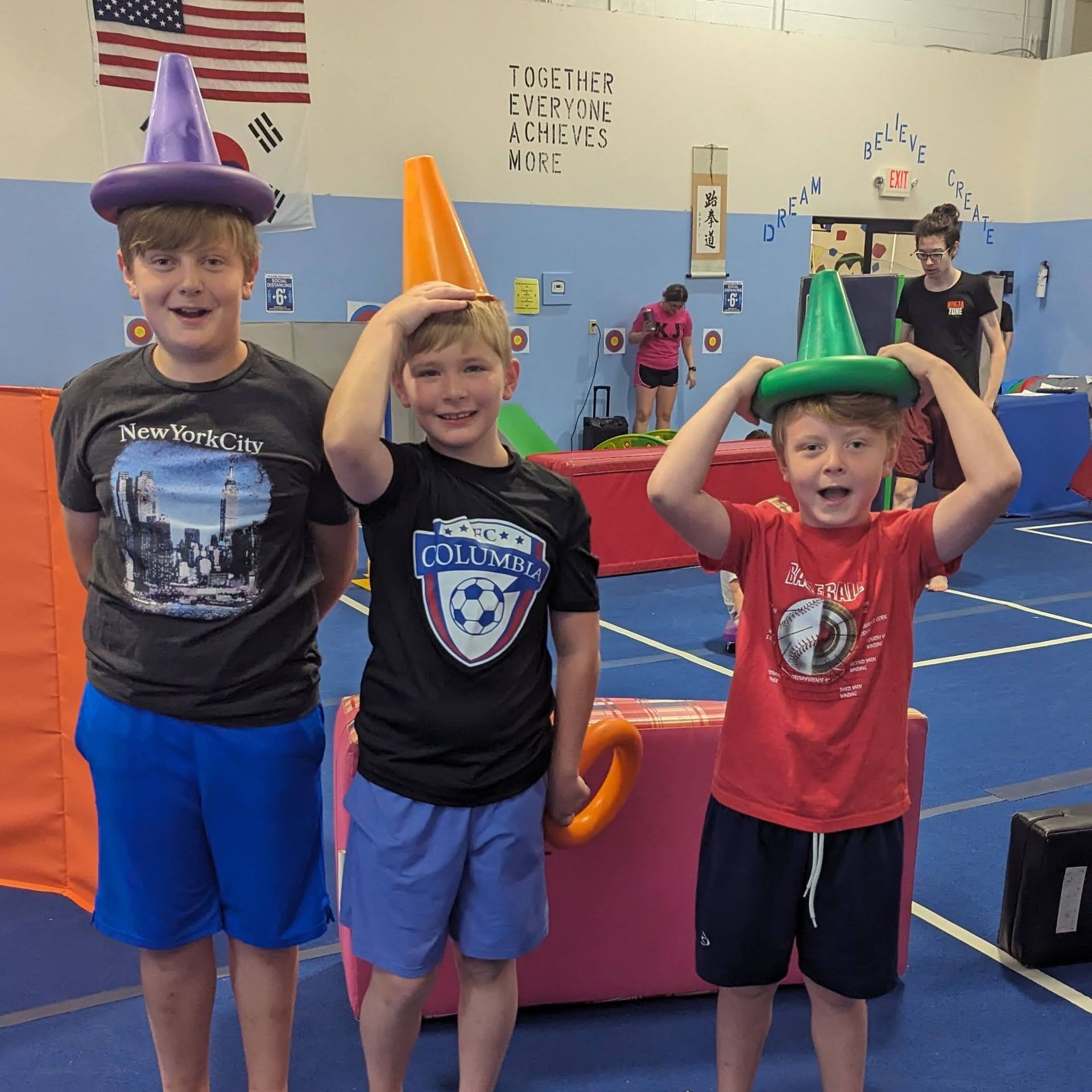 Three young boys are standing in a gym wearing hats and shirts that say california