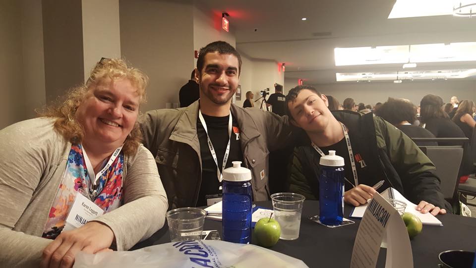 A group of people are sitting at a table with water bottles and apples.