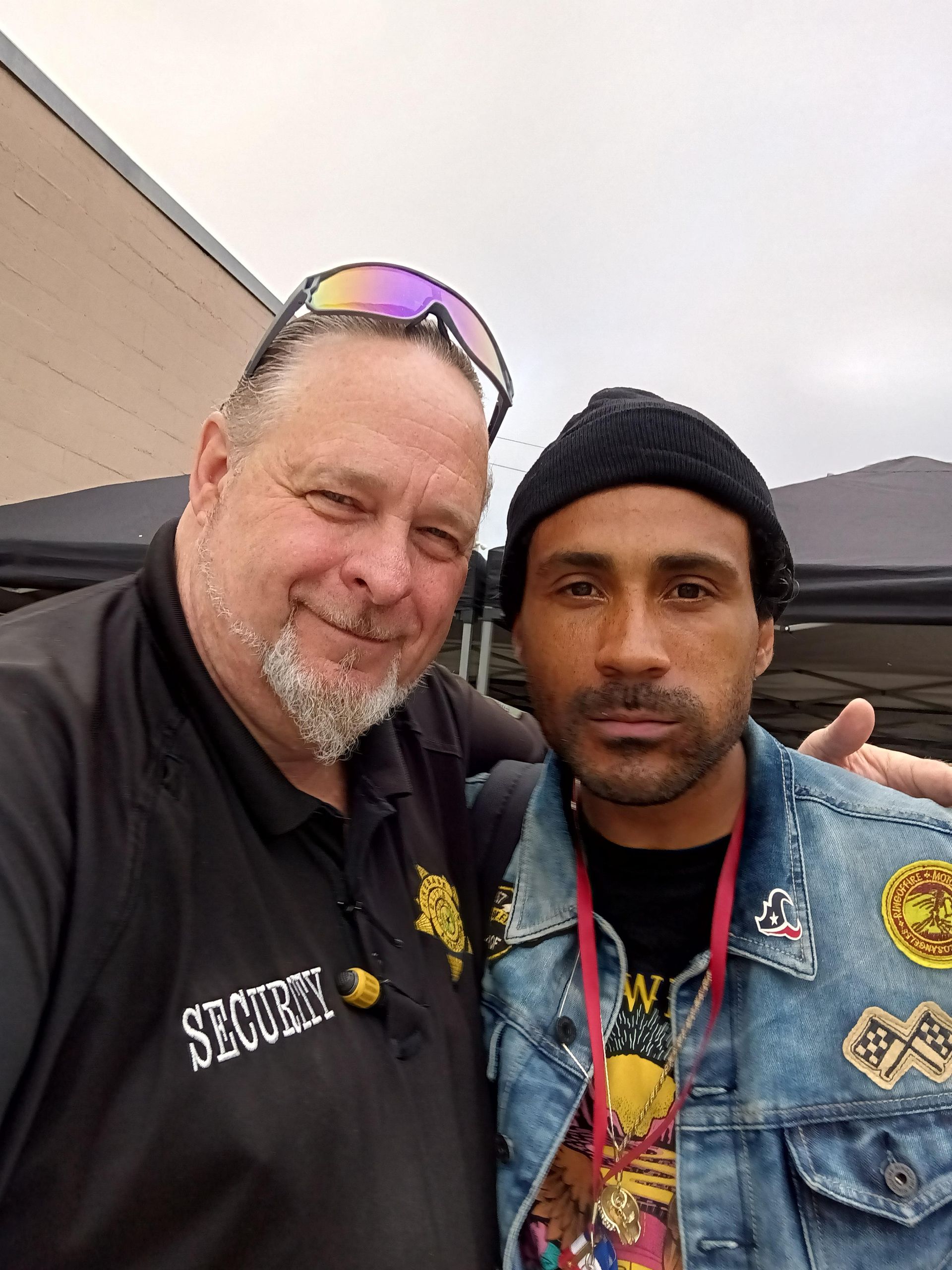 Two men posing for a picture with one wearing a security shirt