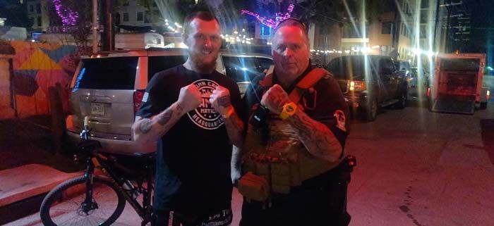 Two men are standing next to each other on a street.