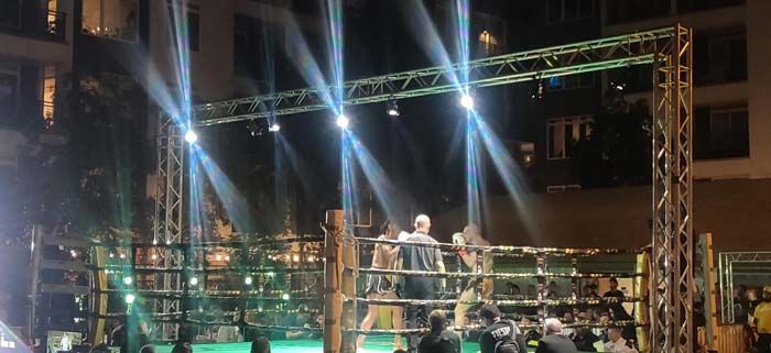 A group of people are standing in a boxing ring at night.