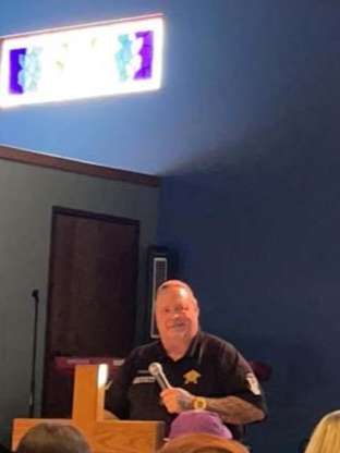 A man is standing at a podium holding a microphone in front of a group of people.