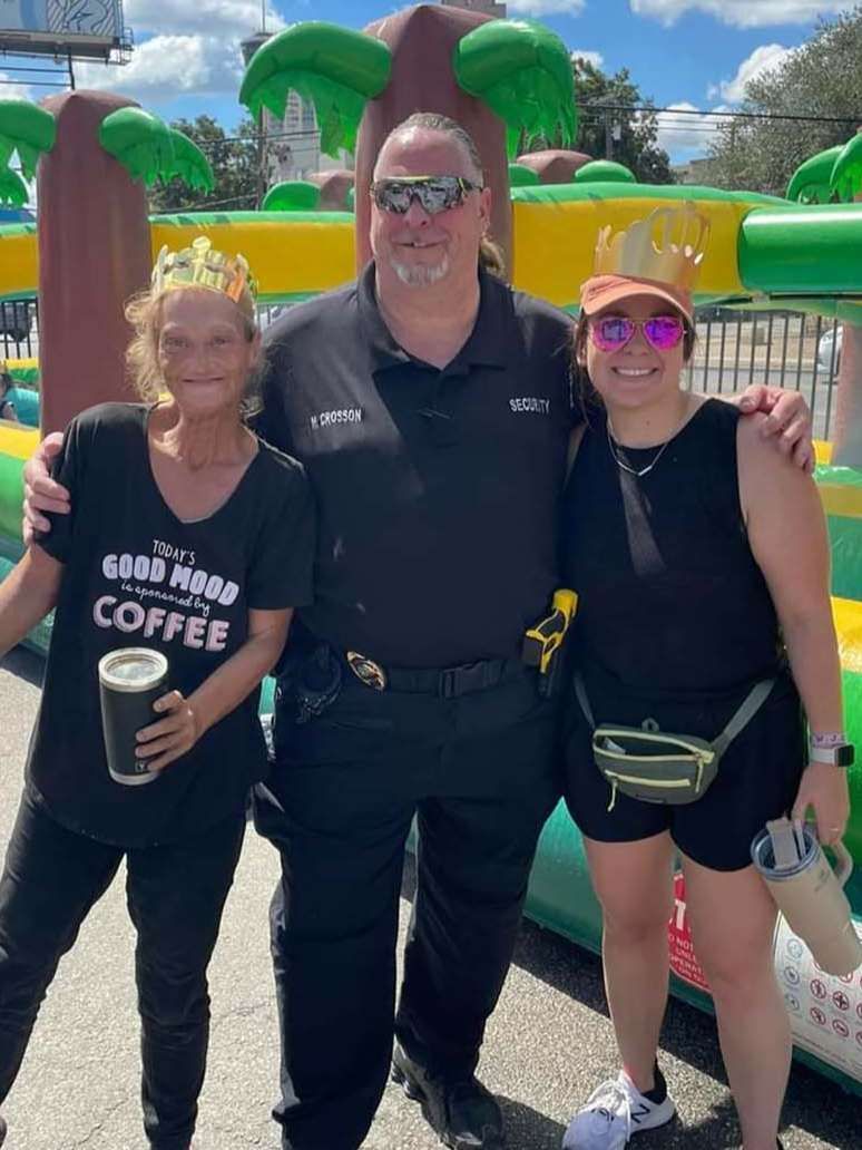 A man and two women are posing for a picture in front of a bouncy house.