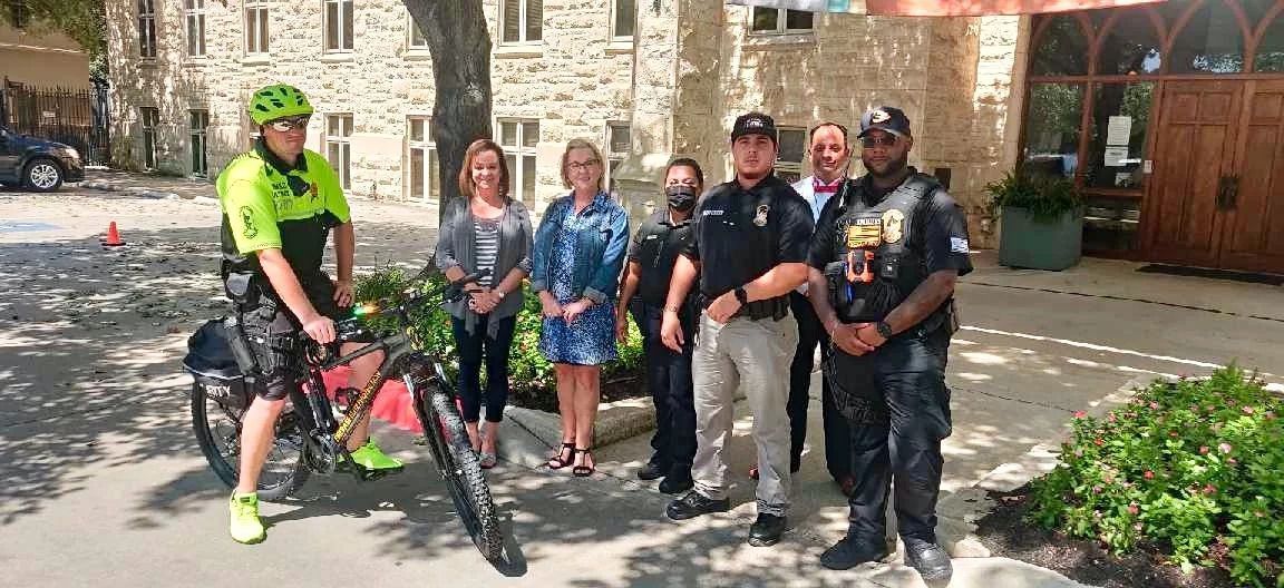 A group of people standing next to each other on a sidewalk.