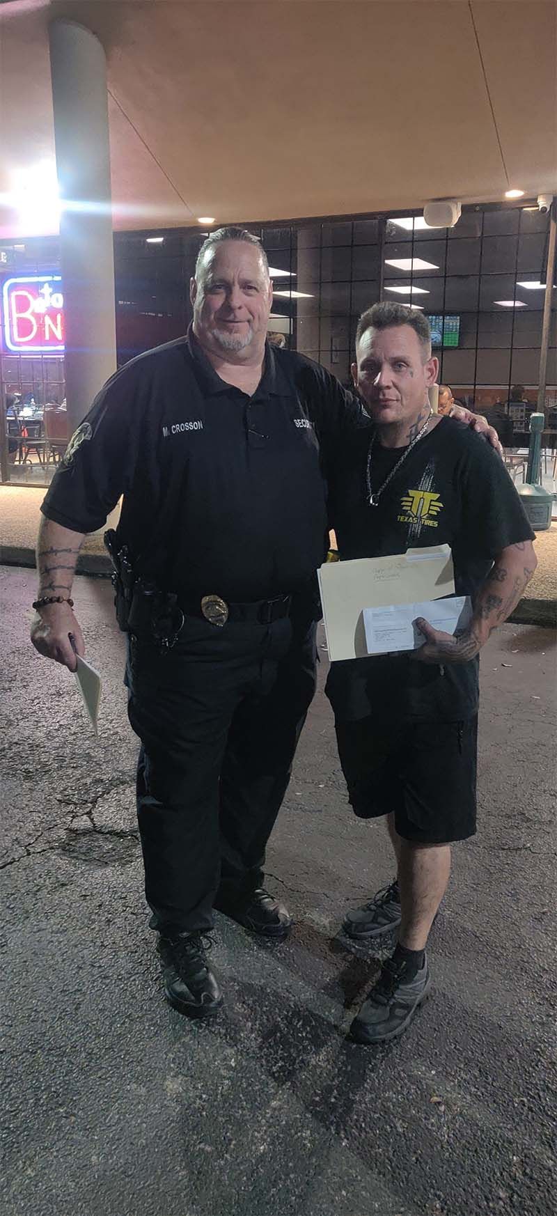 A police officer is standing next to a man holding a piece of paper.