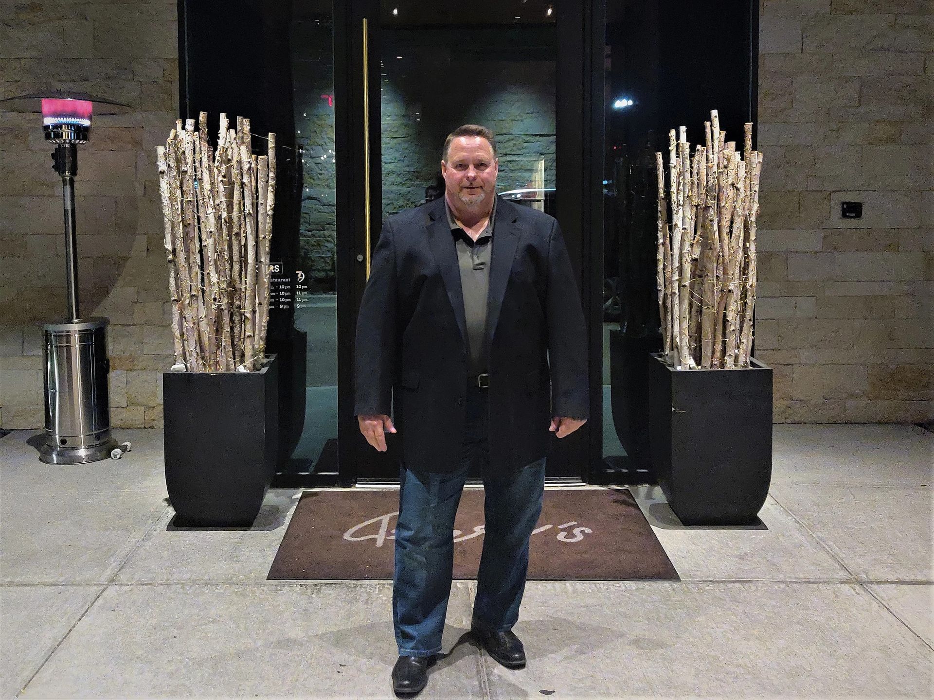 A man in a suit is standing in front of a building