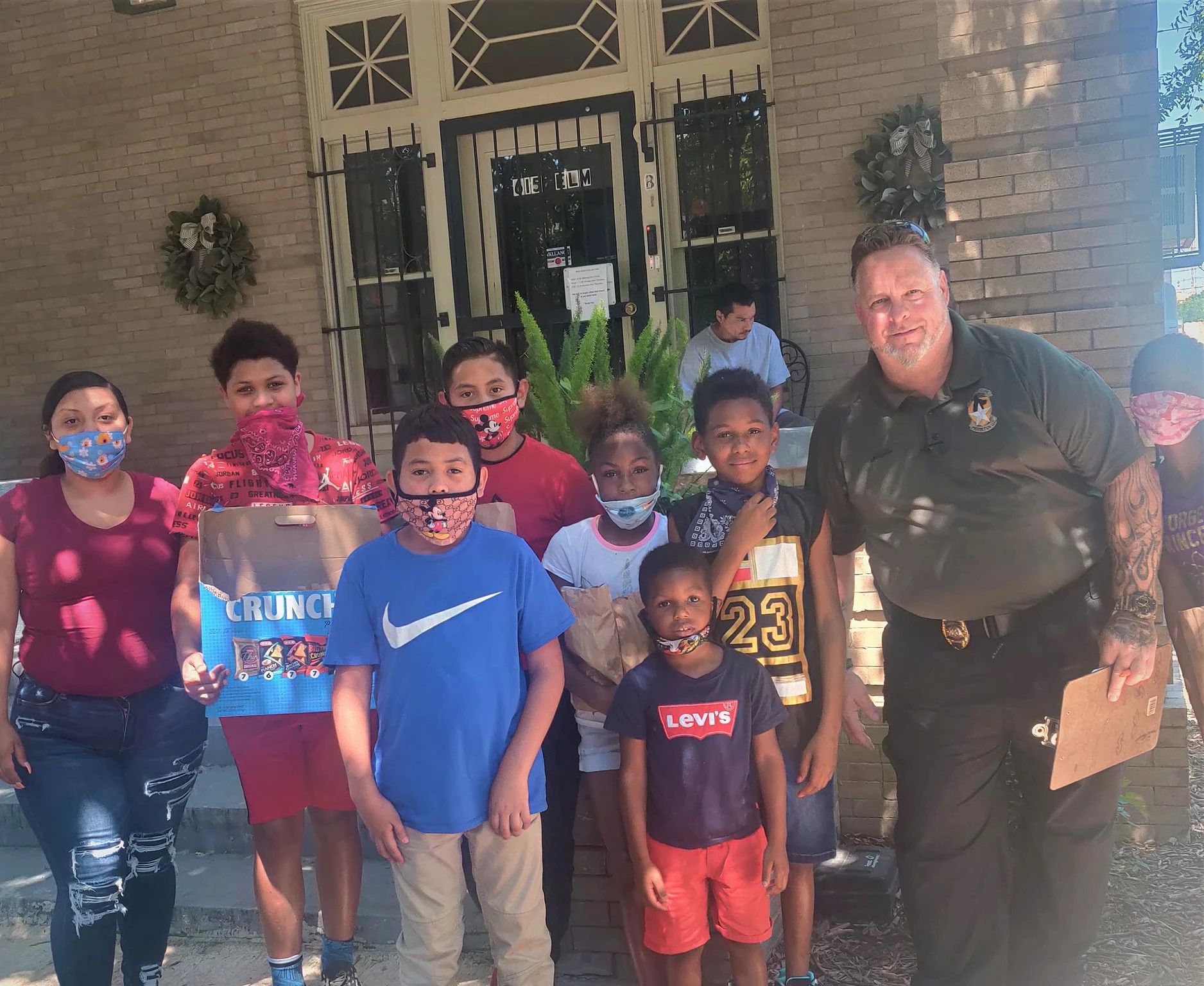A group of children wearing face masks are posing for a picture with a police officer.