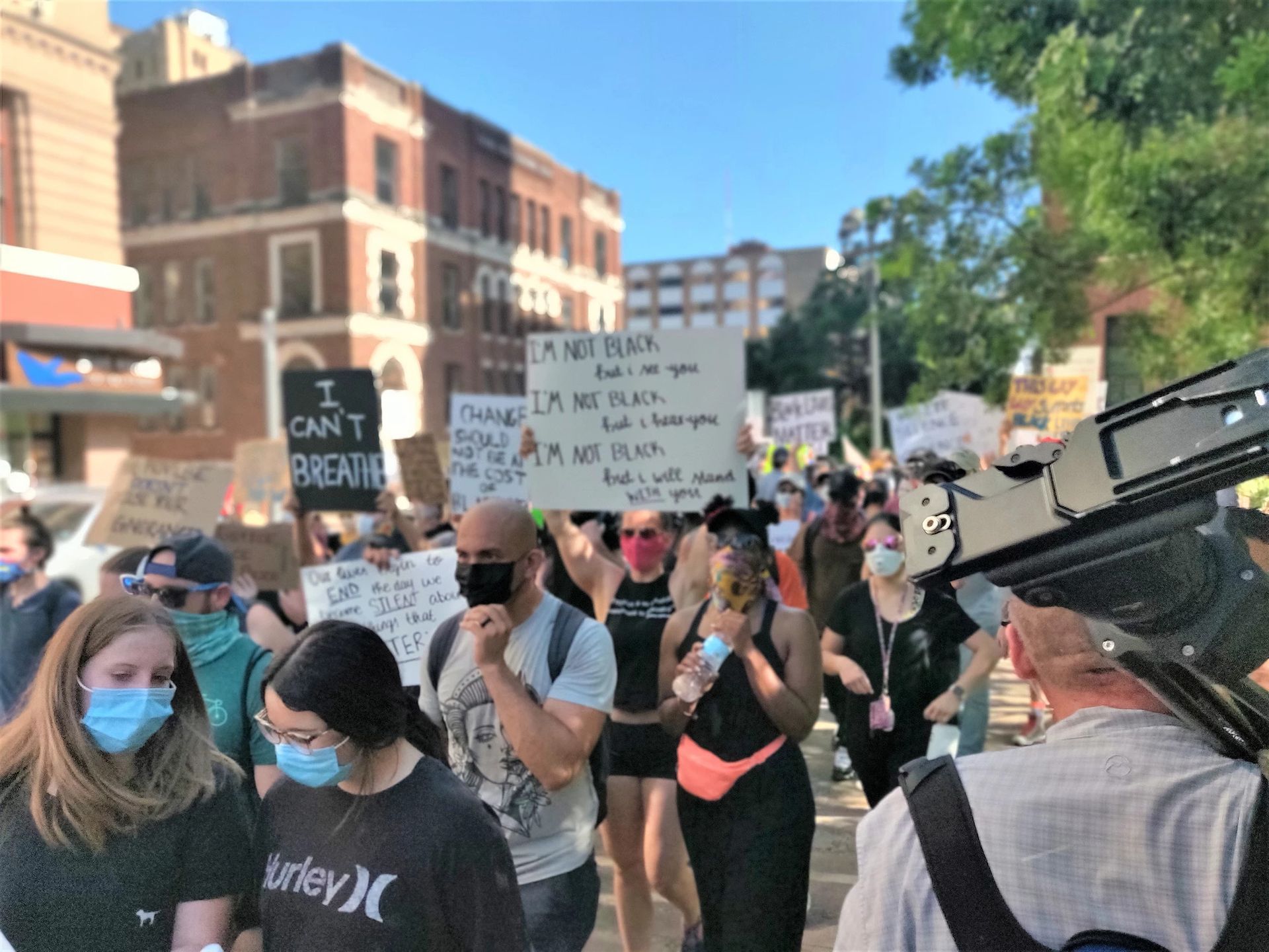 A group of people wearing masks and holding signs including one that says i can 't breathe