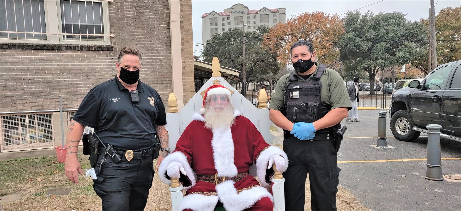 Two police officers are standing next to a man dressed as santa claus.