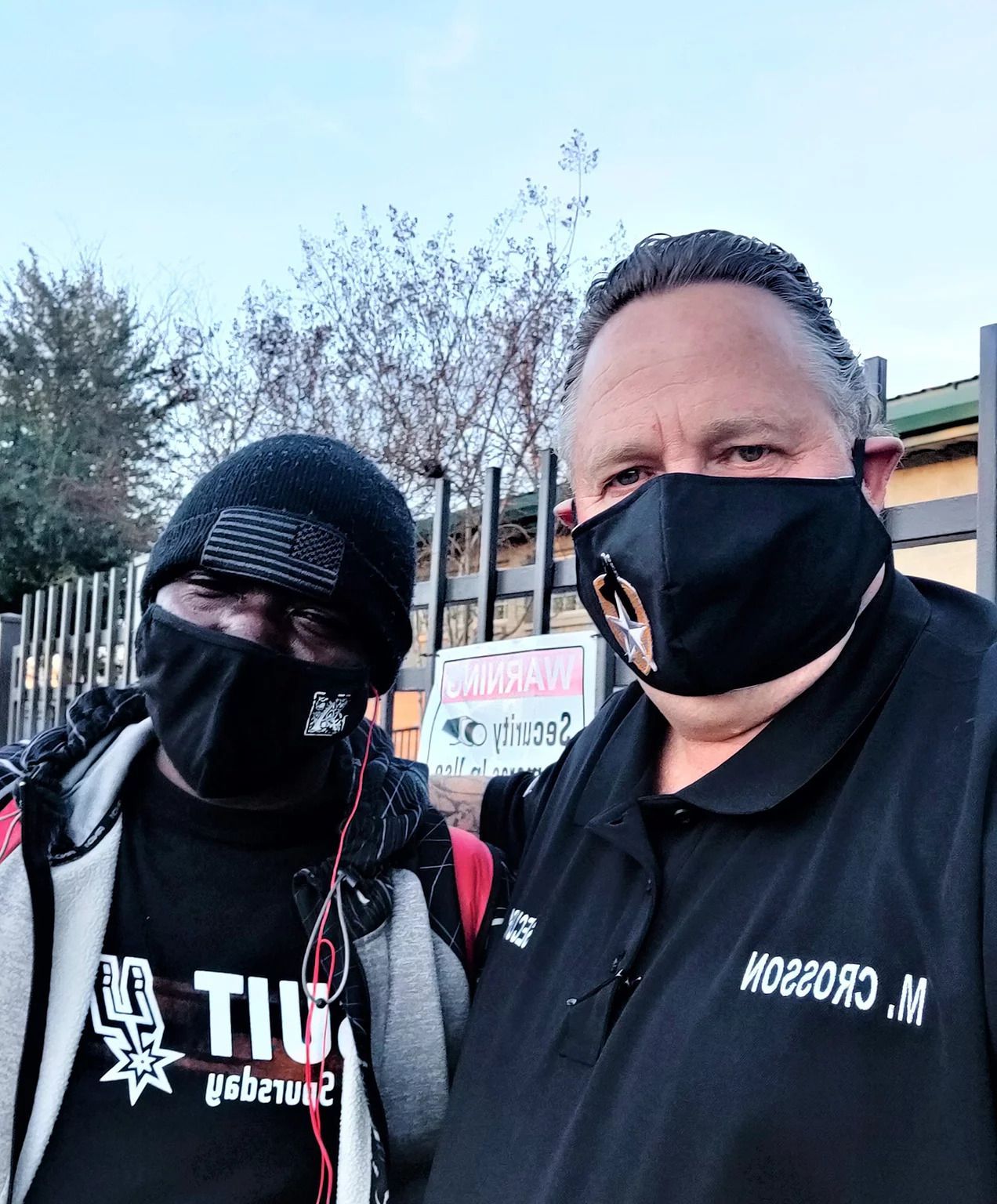 Two men wearing face masks are posing for a picture