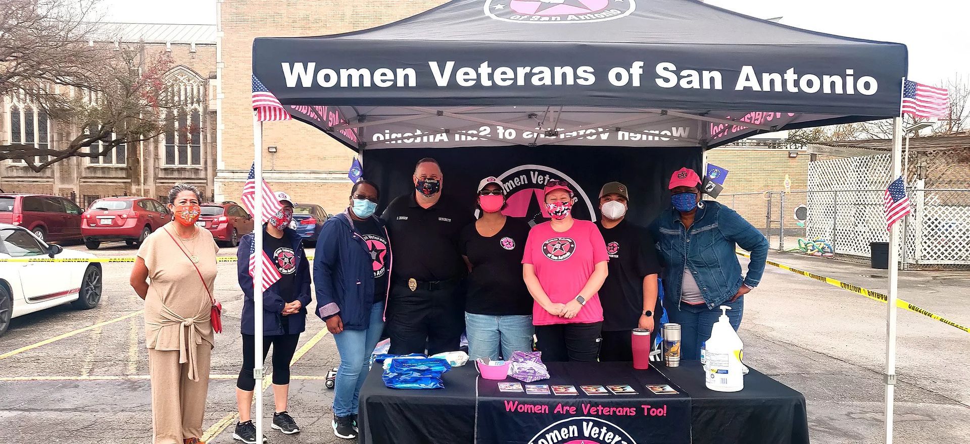 A group of people are standing under a tent that says women veterans of san antonio.