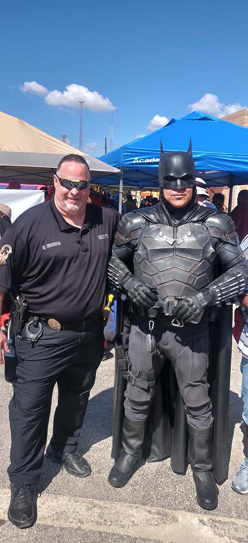 A police officer and a man in a batman costume are posing for a picture.