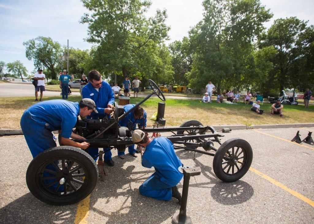 A group of men are working on a car in a parking lot