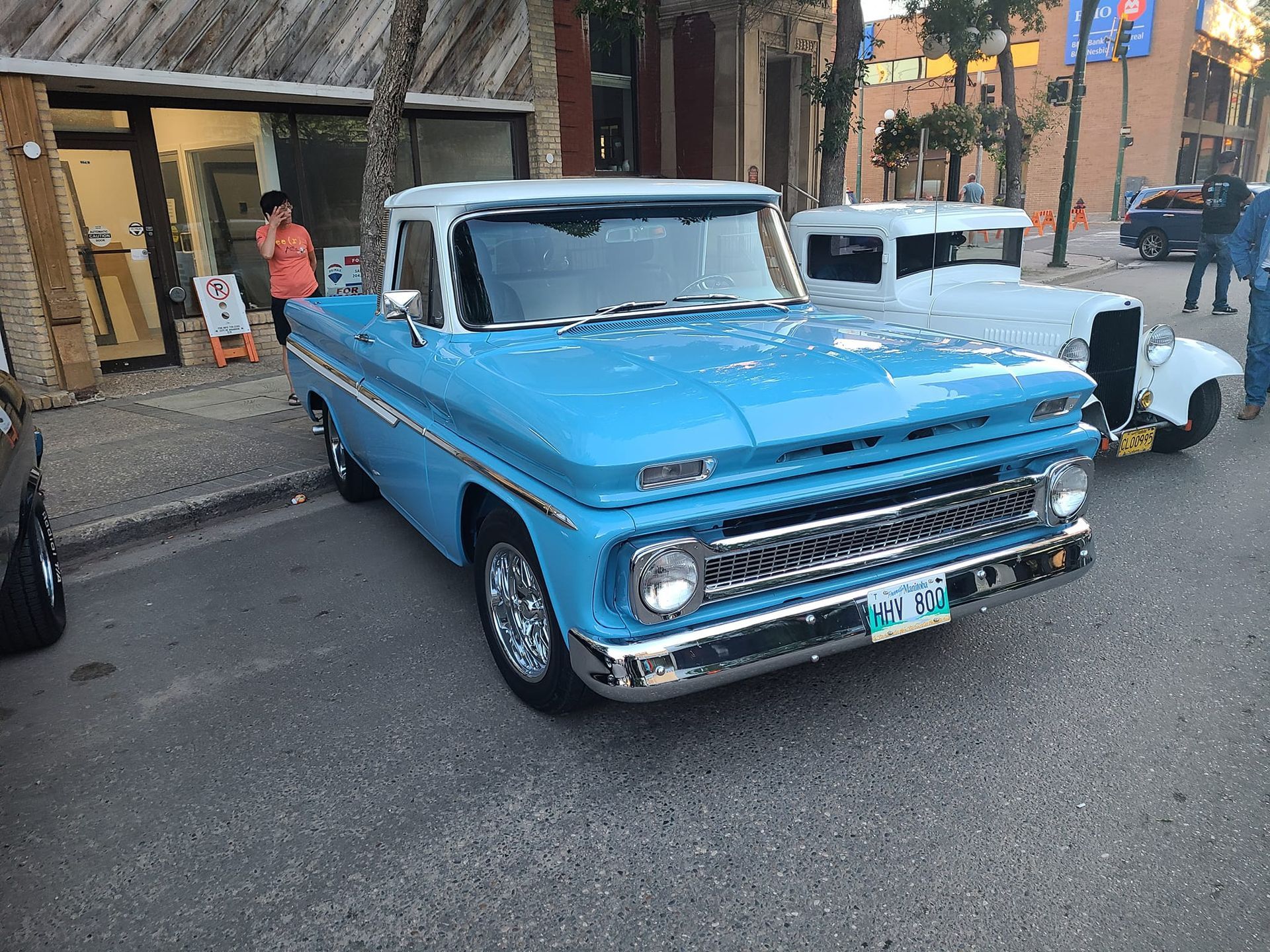 A blue truck is parked on the side of the road in front of a building.