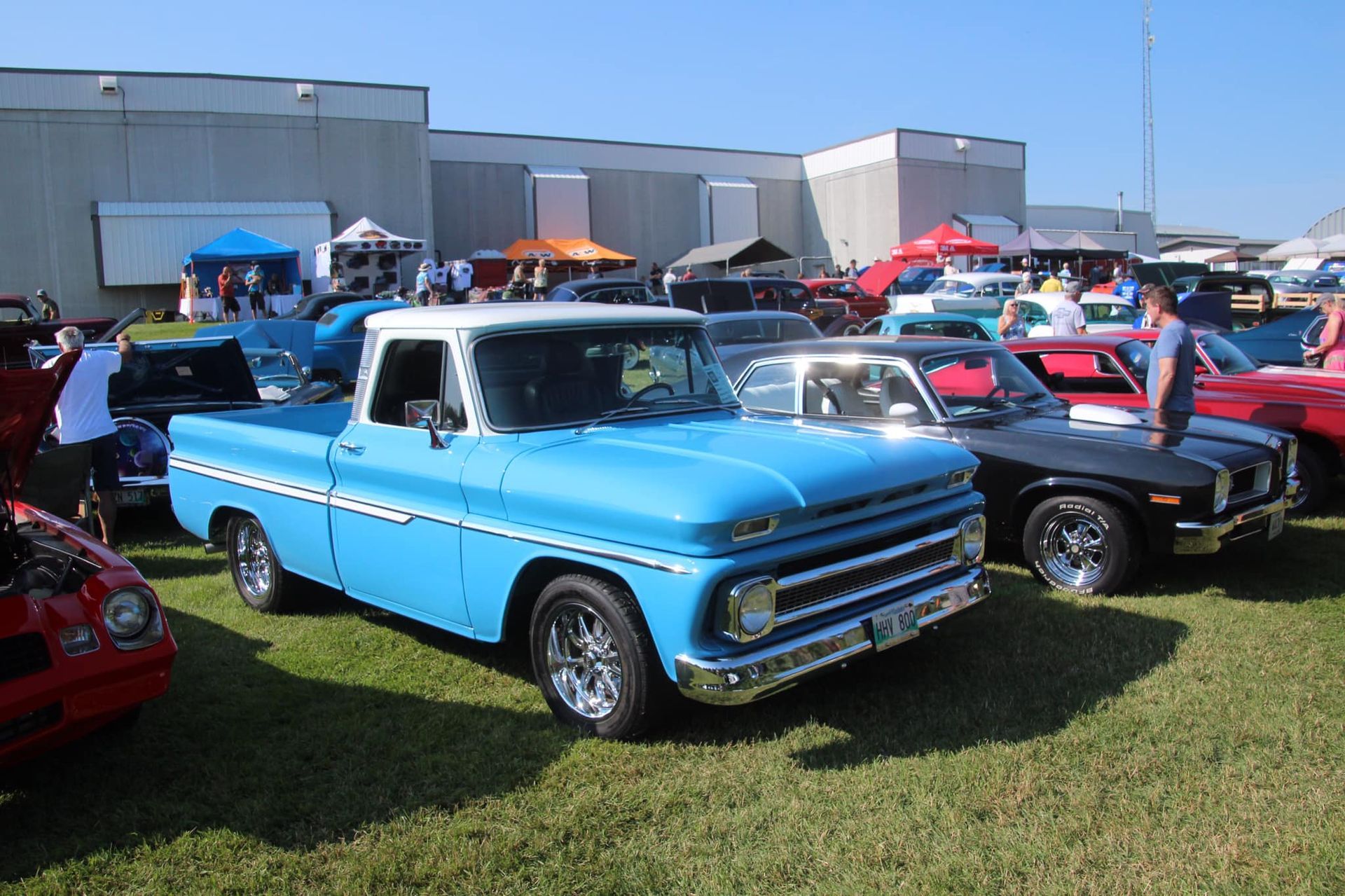 A blue truck is parked in a field with other cars