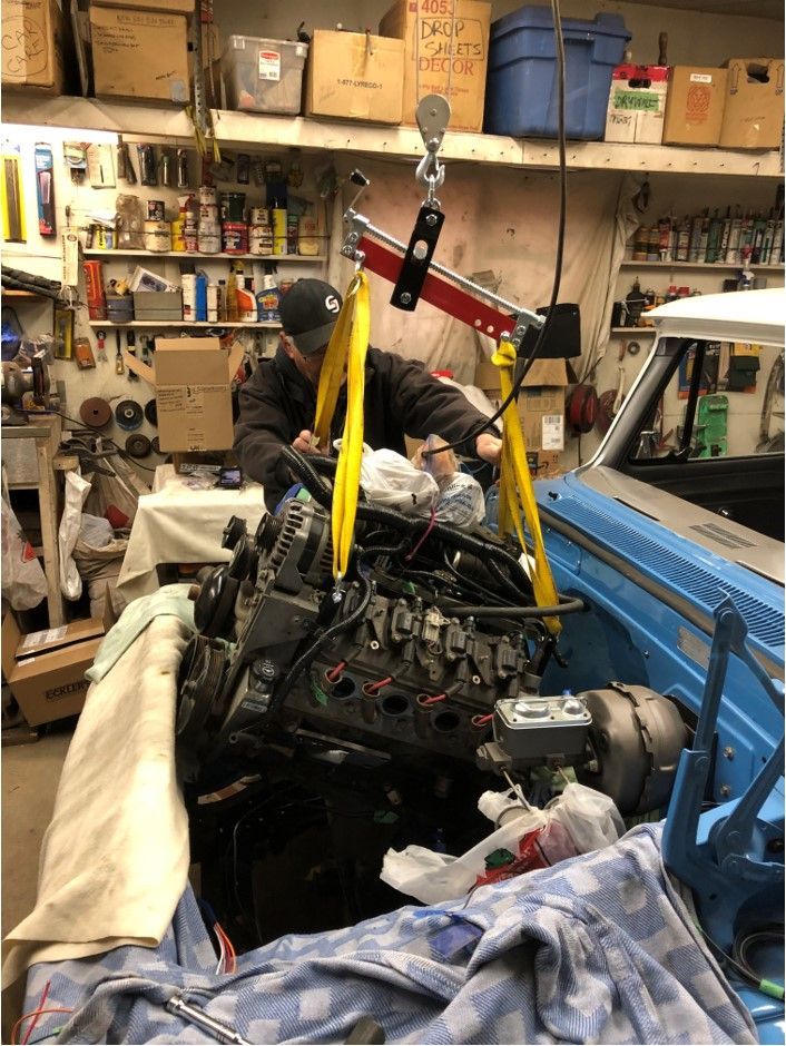 A man is working on a car engine in a garage.